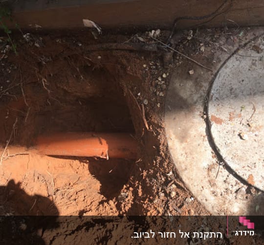 צינור כתום באדמה ליד מכסה ביוב